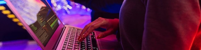 Profissional segurando notebook com tela exibindo painel de monitoramento de segurança da informação com indicadores de ameaças, controles ativos e dashboards de conformidade.
